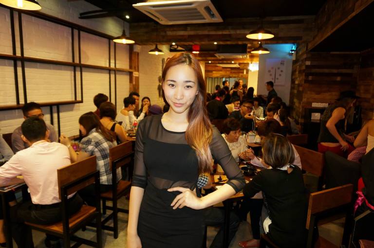 Radio DJ Melissa Thng inside the outlet. The interior of the outlet is a mix of dark wood and white walls with tables for dining as well as a couple of sofas for lounging.