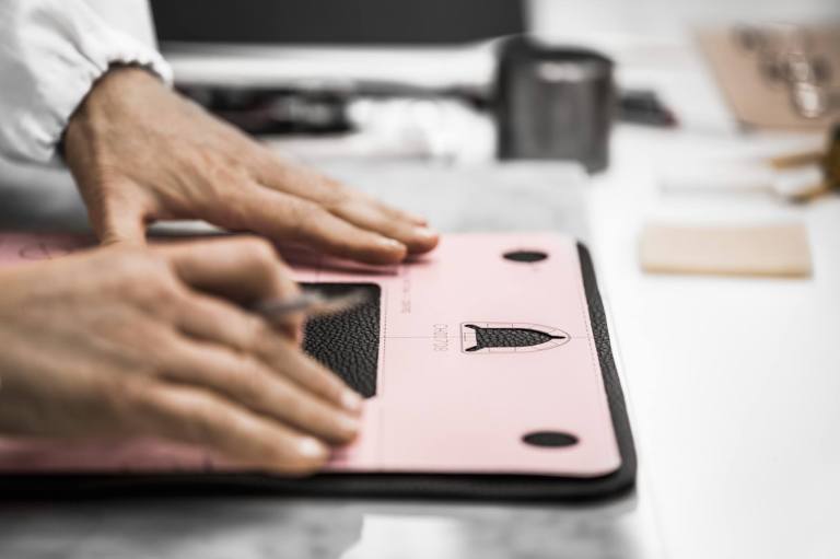 The craftsman uses a pattern for the placement of the badge-shaped clasp.