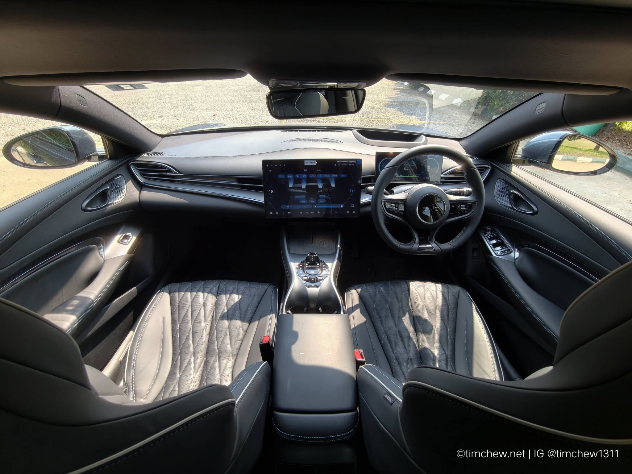 Interior view of a modern car featuring a sleek design with black leather seats, a central touchscreen display, and a sporty steering wheel.