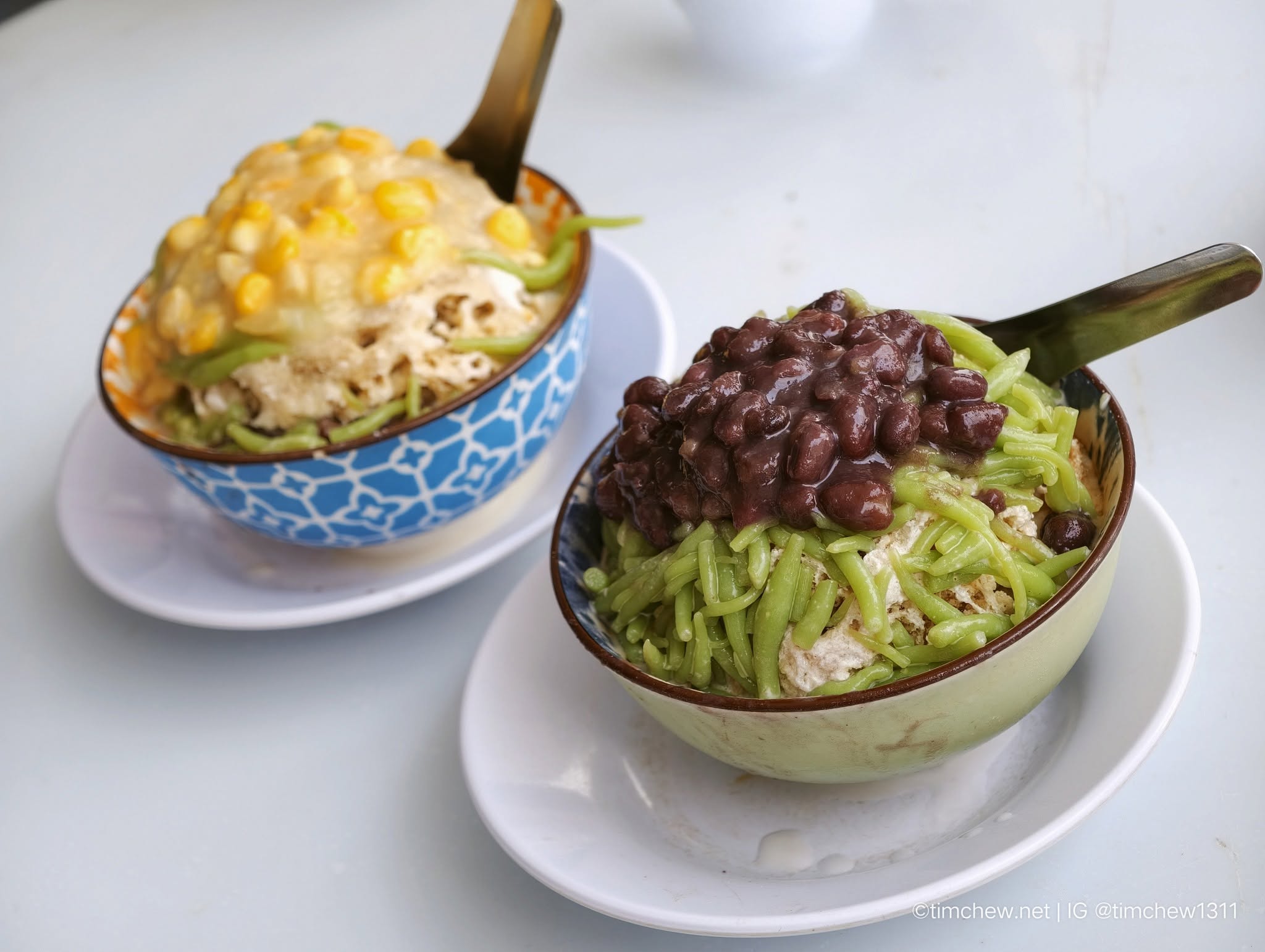 Two bowls of colorful dessert: one topped with sweet corn and creamy texture, and the other with green vermicelli and red beans.