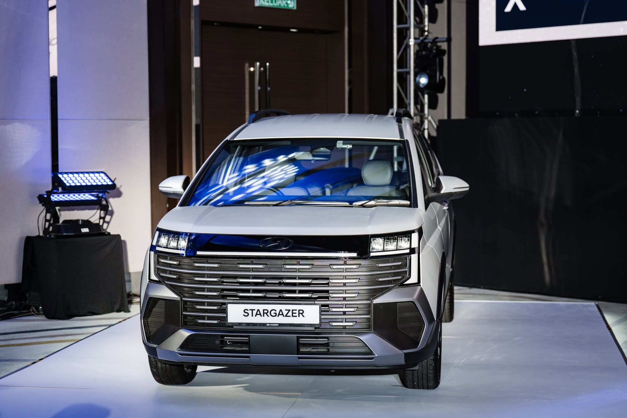 Front view of a white SUV displayed on a stage, featuring a prominent grille and the name 'STARGAZER' prominently featured.