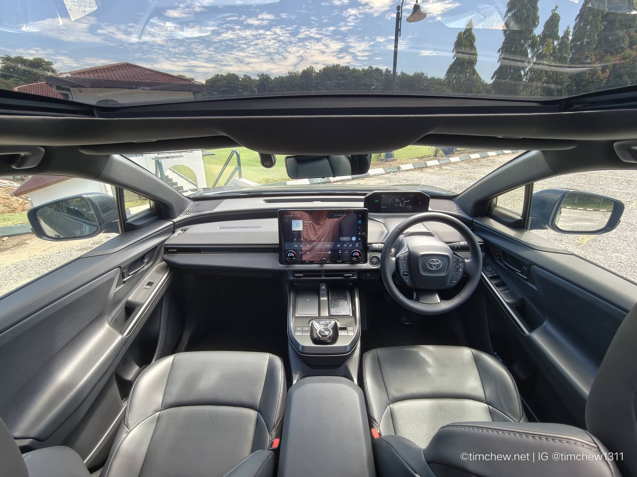 Interior view of a modern car showcasing black leather seats, a touchscreen display on the dashboard, and a panoramic sunroof.
